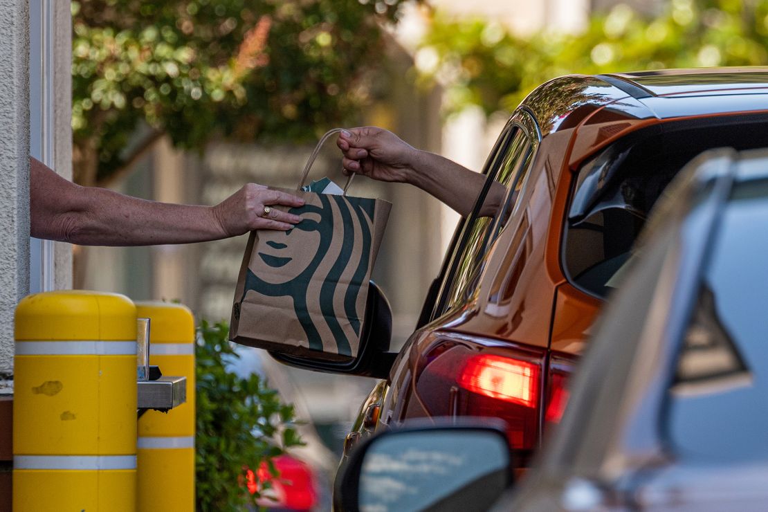 An employee hands a bag to a customer at the drive-thru of a Starbucks coffee shop in Hercules, California, on July 28, 2022.