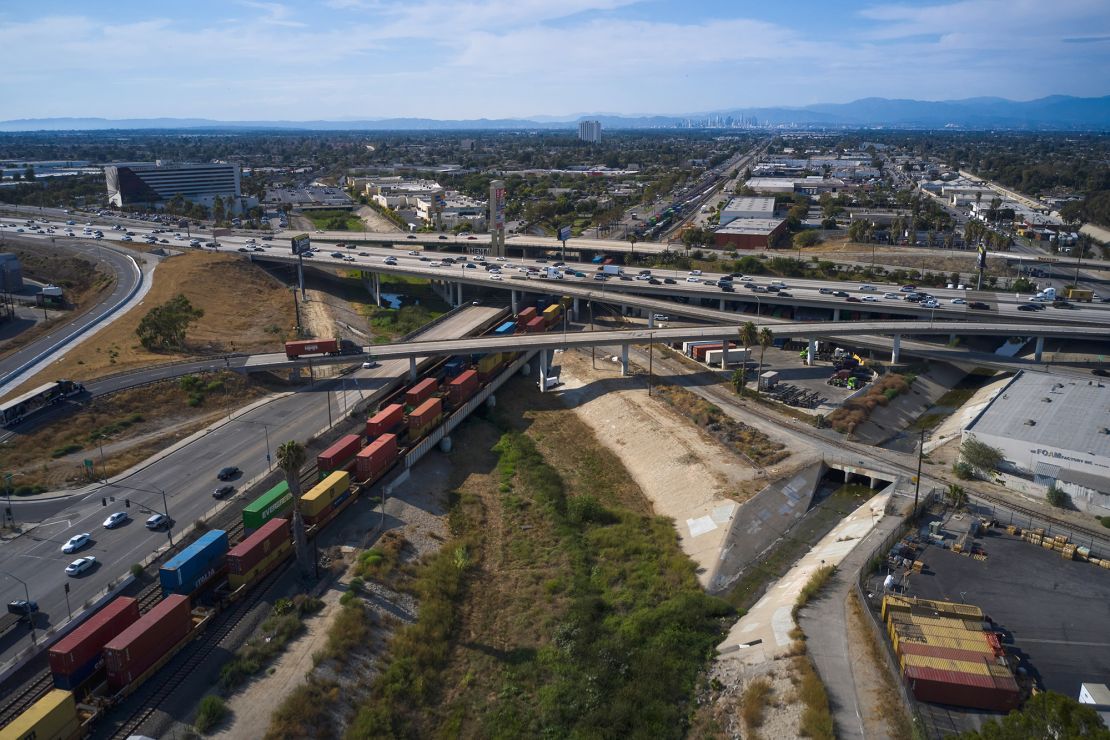 Uma longa fila de contêineres de carga passa sob uma rodovia em Compton, Califórnia, EUA, na terça-feira, 2 de agosto de 2022.