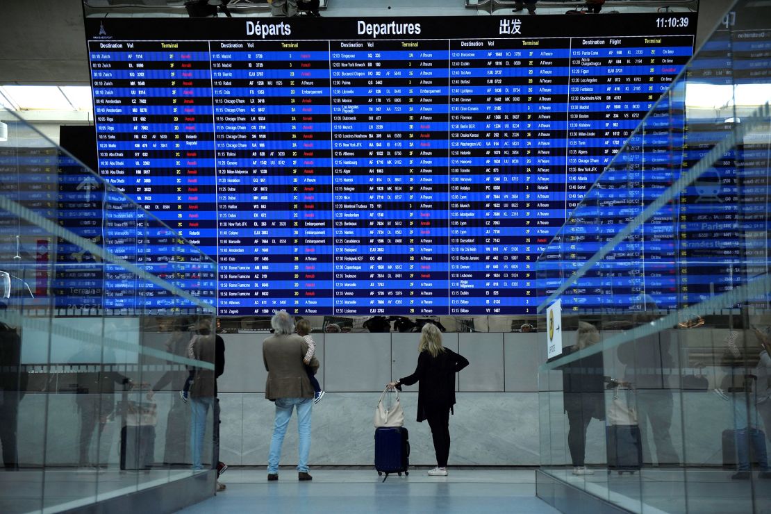 Travelers look at the departure information at Paris Charles de Gaulle Airport. If your flight is delayed or canceled after you've already arrived, make a beeline to the airline agents' desk.