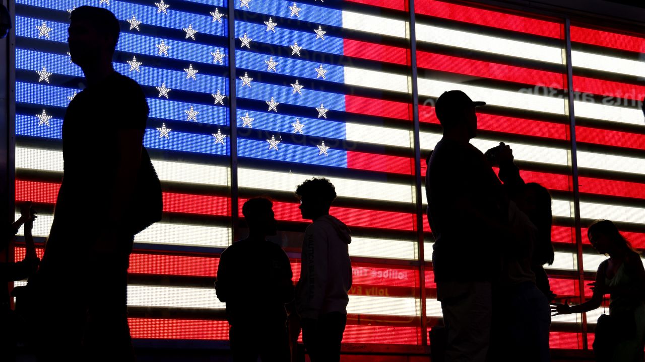 People stand in front of a US flag on a screen in Times Square in New York on September 19, 2022.