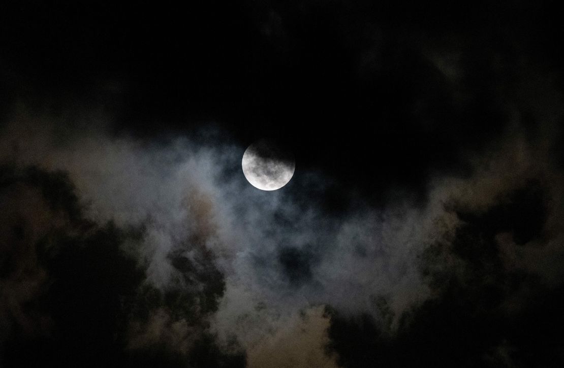 The Moon is visible through clouds during a partial lunar eclipse over Caracas, Venezuela, early on November 8, 2022.