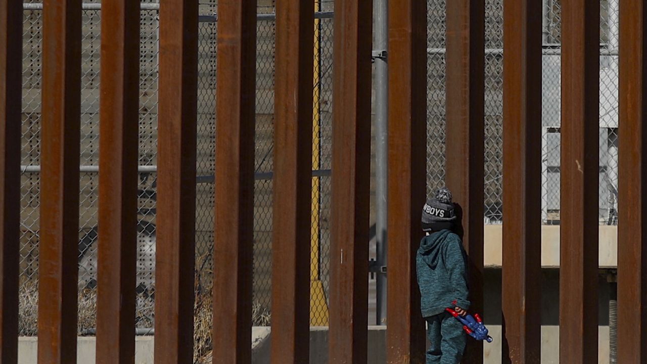 TOPSHOT - Venezuelan migrant George, 5, stands by the bars of the border wall holding a Captain America action figure while staying with his family on the Rio Grande river in Ciudad Juarez, Chihuahua state, Mexico on December 27, 2022. - The US government's two-year-old policy of invoking Covid-19 precautions to turn away hundreds of thousands of migrants at the Mexican border will remain in place for now, the Supreme Court ruled Tuesday. The decision to uphold the controversial rule known as Title 42 stemmed off a looming political crisis for President Joe Biden, as thousands waited at the southern border in expectation the policy was about to end. (Photo by Herika Martinez / AFP) (Photo by HERIKA MARTINEZ/AFP via Getty Images)