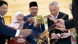 Singapore Deputy Prime Minister Lawrence Wong (L), Malaysian Prime Minister Anwar Ibrahim (3rd L) and his wife Wan Azizah (2nd L), Singapore's Prime Minister Lee Hsien Loong (2nd R) and his wife Ho Ching (R) mix a traditional Chinese lunar new year dish Yusheng during a lunch at the Istana Presidential Palace in Singapore on January 30, 2023. (Photo by HOW HWEE YOUNG / POOL / AFP) (Photo by HOW HWEE YOUNG/POOL/AFP via Getty Images)