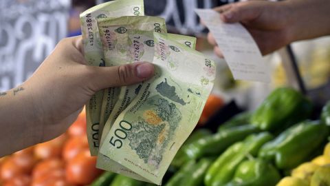 A woman pays for fruits and vegetables at a retail stall of the Central Market of Buenos Aires on February 10, 2023, some days before the announcement of the monthly inflation index. - The "Precios Justos" programme which regulates prices and was agreed between the Argentine Government and businessmen as a measure to fight inflation has recently recorded a rise in prices. (Photo by JUAN MABROMATA / AFP) (Photo by JUAN MABROMATA/AFP via Getty Images)