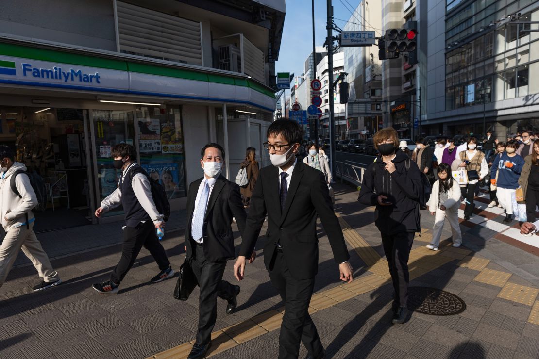 Businessmen walk towards Shinjuku station in Tokyo.