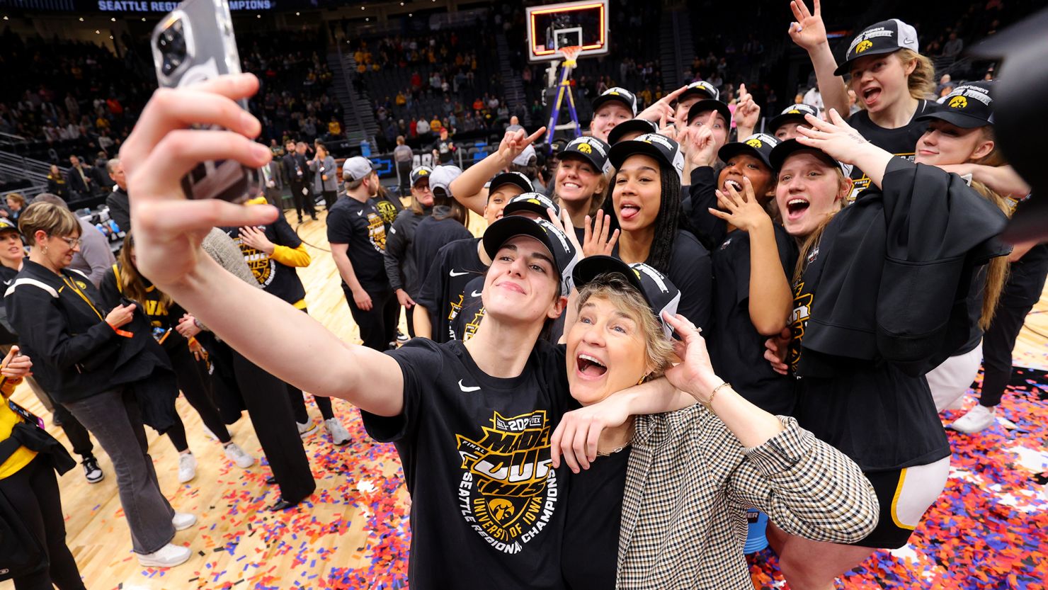 Caitlin Clark of the Iowa Hawkeyes takes a selfie with head coach Lisa Bluder after the Elite Eight round of the 2023 NCAA Women's Basketball Tournament. Clark drew enormous attention to the women’s Tournament.
