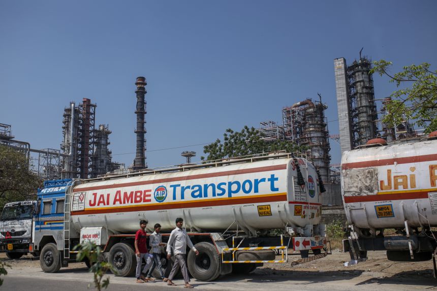 People walk by an oil refinery operated by Bharat Petroleum in Mumbai, India, on April 4, 2023.