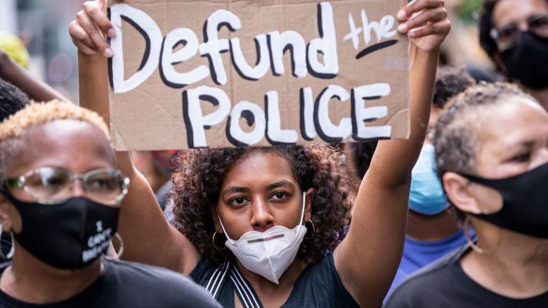 A protester wears a mask and holds a homemade sign that says, "Defund the Police" during a peaceful protest walk across the Brooklyn Bridge on June 19, 2020.