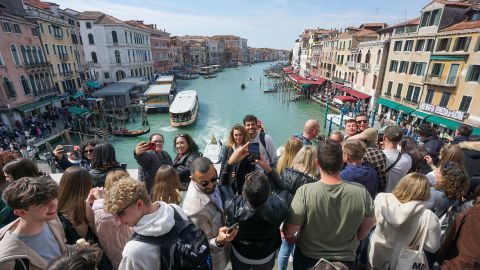 Tourists take photographs on the Rialto Bridge in Venice, Italy, on Saturday, April 8, 2023. Italy's upcoming budget outlook will probably incorporate a higher growth forecast for 2023 followed by a worsened outlook for subsequent years, according to people familiar with the matter. Photographer: Andrea Merola/Bloomberg via Getty Images