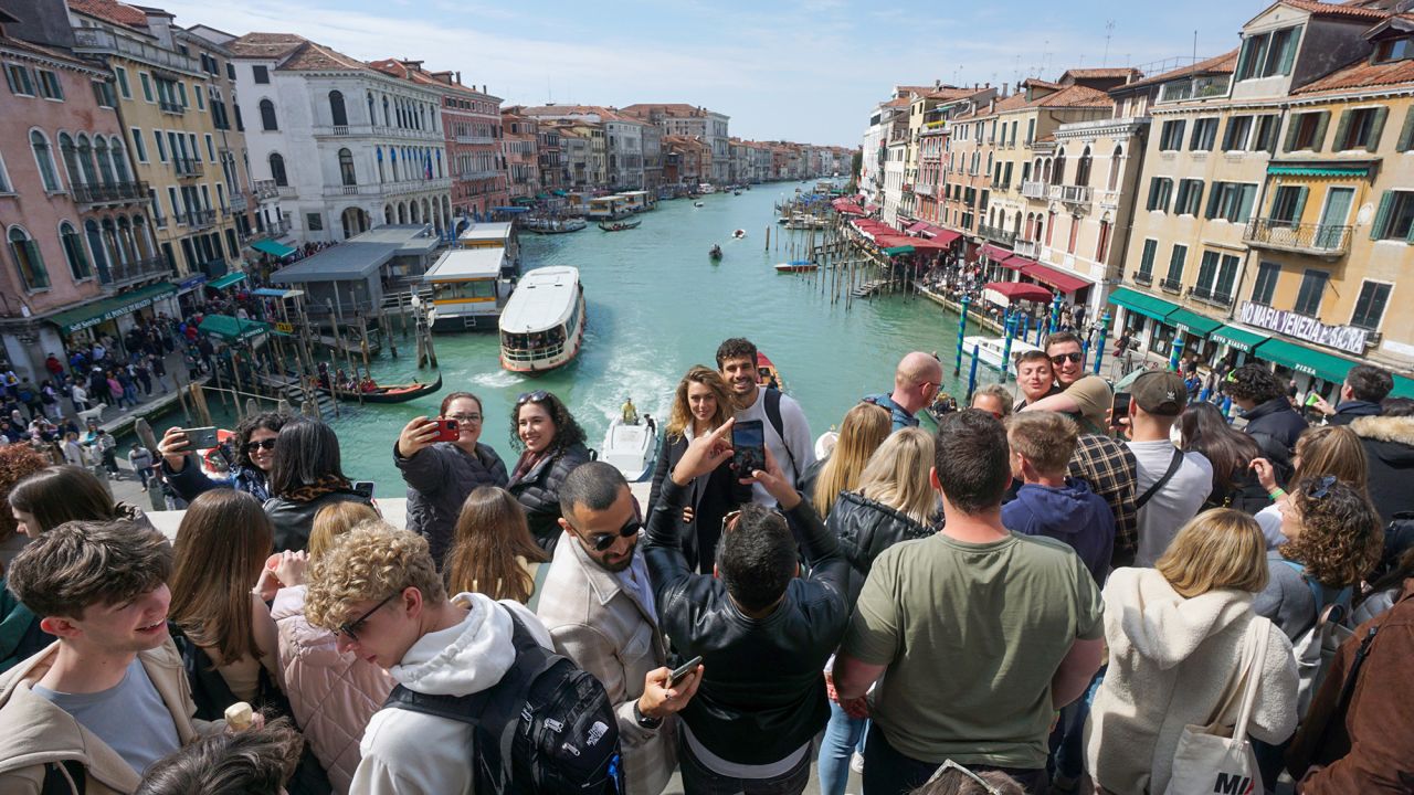 Tourists take photographs on the Rialto Bridge in Venice, Italy, on Saturday, April 8, 2023. Italy's upcoming budget outlook will probably incorporate a higher growth forecast for 2023 followed by a worsened outlook for subsequent years, according to people familiar with the matter. Photographer: Andrea Merola/Bloomberg via Getty Images
