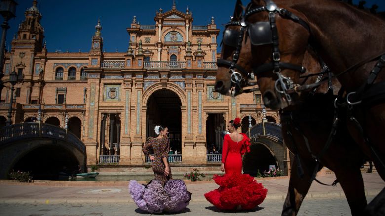 TOPSHOT - Woman wearing traditional Andalusian dresses stand on Plaza de Espana in Seville as Spain is bracing for an early heat wave on April 24, 2023. - Drought-hit Spain is bracing for an early heat wave this week with temperatures forecast to hit 40 degrees Celsius (104 Fahrenheit) in some places, another sign of climate change. (Photo by JORGE GUERRERO / AFP) (Photo by JORGE GUERRERO/AFP via Getty Images)