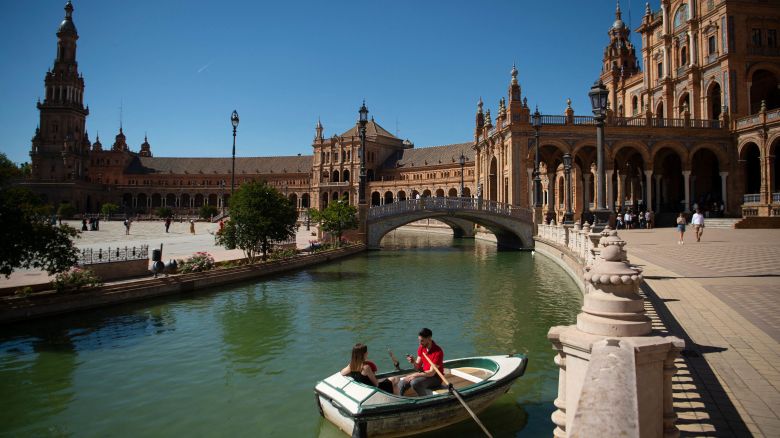 A couple sail on a boat for rent on Plaza de Espana in Seville on April 24, 2023 as Spain is bracing for an early heat wave. - Drought-hit Spain is bracing for an early heat wave this week with temperatures forecast to hit 40 degrees Celsius (104 Fahrenheit) in some places, another sign of climate change. (Photo by JORGE GUERRERO / AFP) (Photo by JORGE GUERRERO/AFP via Getty Images)