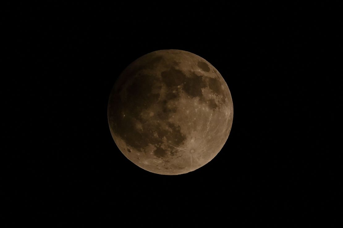 The moon looks slightly darker during a 2023 penumbral lunar eclipse in Banda Aceh, Indonesia. On Monday, the lunar event will begin at 12:53 a.m. ET.