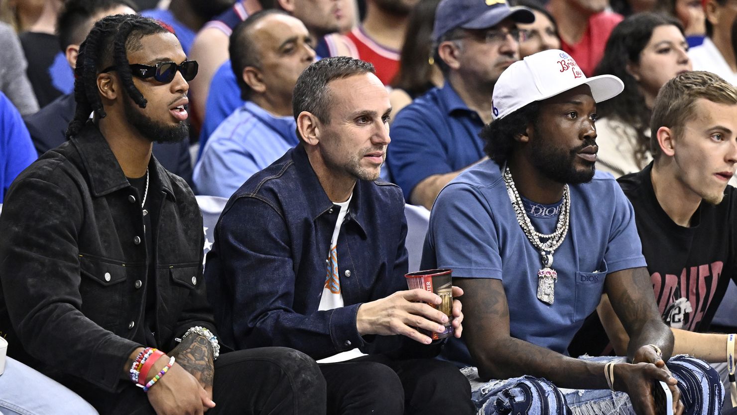Former Sixers managing partner Michael Rubin (middle) sits courtside alongside NFL safety Damar Hamlin (L) and rapper Meek Mill (R).