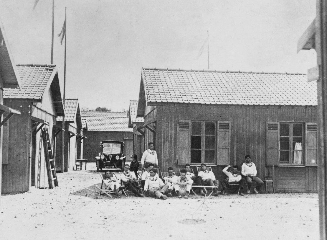 Athletes sitting in front of a cabin in the Olympic Village at the 1924 Summer Olympics in Paris, France. The 1924 Games were the first Games to have an Olympic Village, with a number of cabins built near the stadium to accommodate visiting athletes.