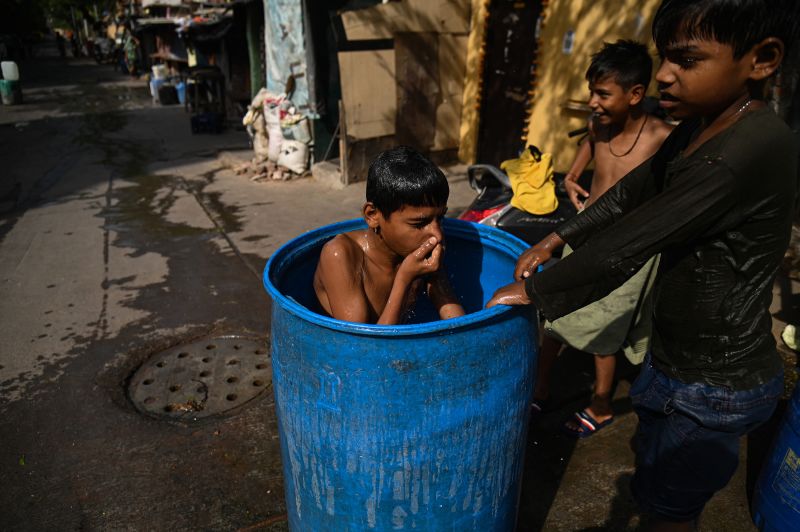 A boy takes a dip in a water container outside his slum dwelling in New Delhi, in May 2023.