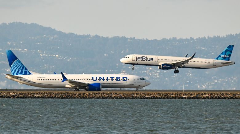 A United Airlines plane prepares for takeoff as a JetBlue plane lands at San Francisco International Airport in 2023.