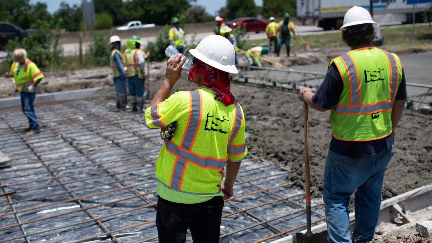 A construction worker takes a sip of water while repairing a road that was damaged from the heat in Houston, Texas on June 27, 2023.