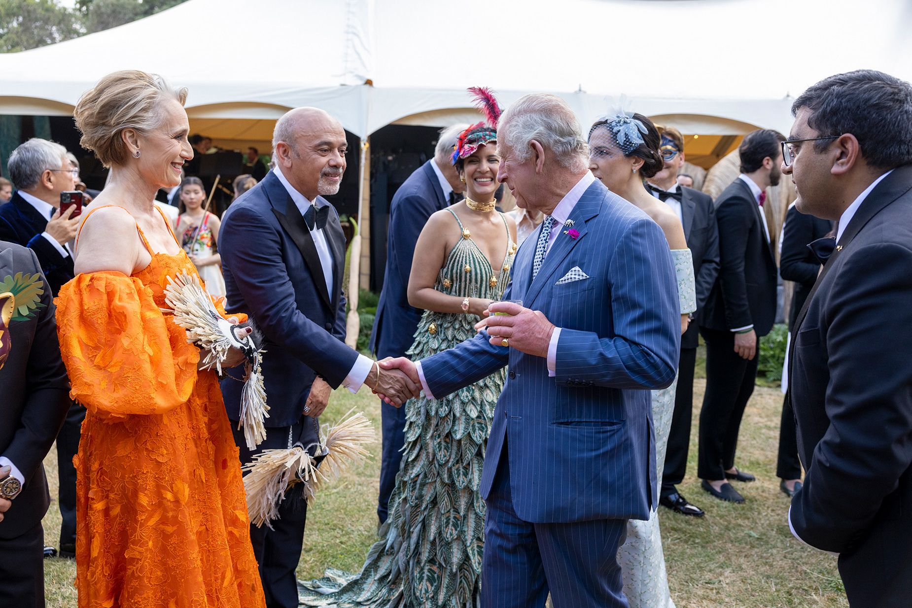 King Charles III speaks with Christian Louboutin and actor Kristin Scott Thomas at a garden party in 2023 in London.