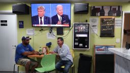 Raul Ortiz and Jose Martin sit in a restaurant under a television broadcasting the first debate between President Donald Trump and Democratic presidential nominee Joe Biden on September 29, 2020 in Miami, Florida.