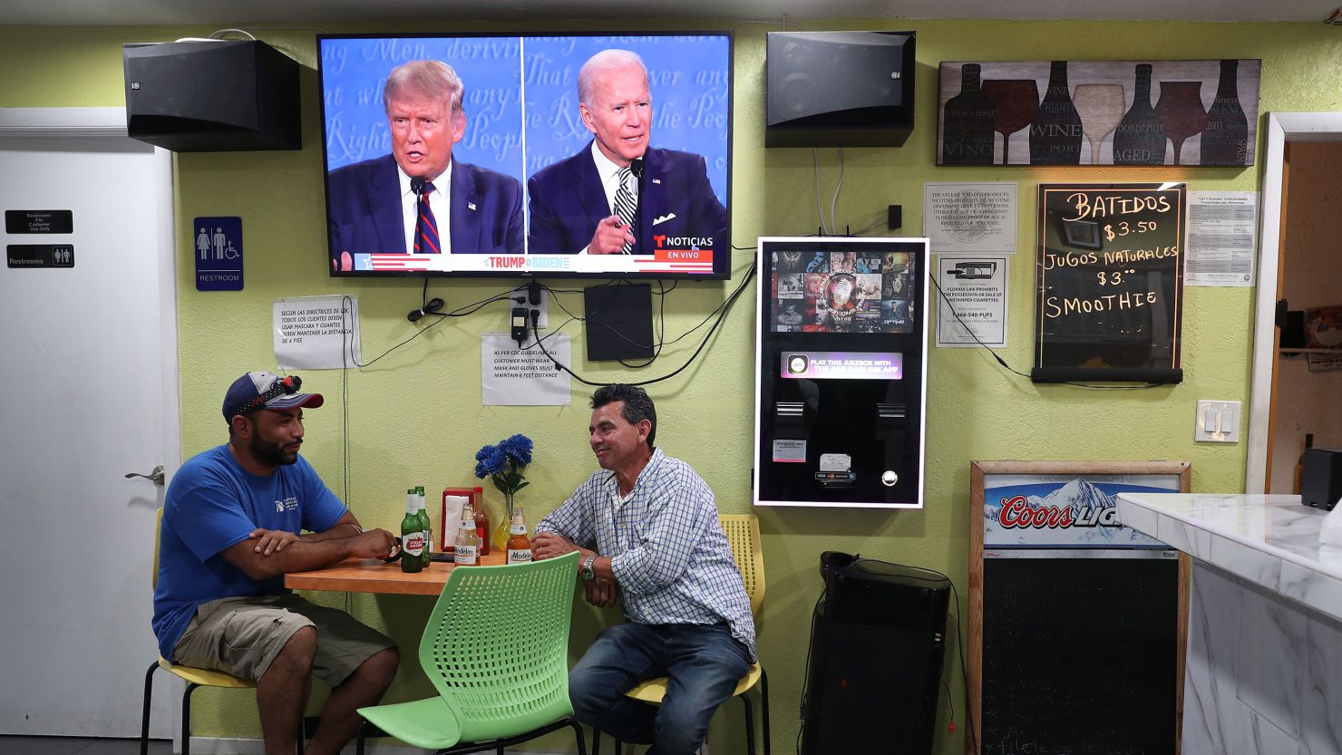 Raul Ortiz and Jose Martin sit in a restaurant under a TV broadcasting the first debate between then-President Donald Trump and then-Democratic presidential nominee Joe Biden on September 29, 2020, in Miami.