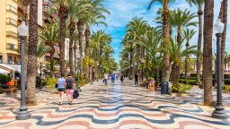 Alicante, Spain - March 29, 2018: People walking on a palm-lined promenade in Alicante, Spain. Alicante is a city located in the southeast of the Iberian Peninsula, on the shores of the Mediterranean Sea. It is the capital of the Alicante province and has about 330,000 inhabitants.
