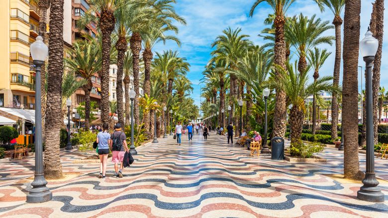 Alicante, Spain - March 29, 2018: People walking on a palm-lined promenade in Alicante, Spain. Alicante is a city located in the southeast of the Iberian Peninsula, on the shores of the Mediterranean Sea. It is the capital of the Alicante province and has about 330,000 inhabitants.