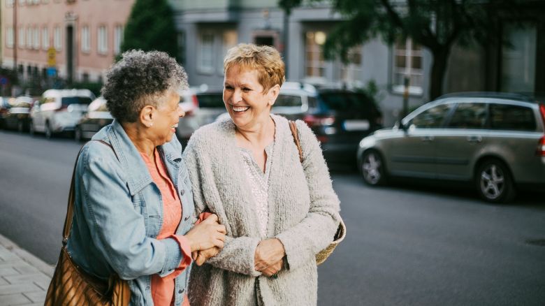 Cheerful older female friends talking in city