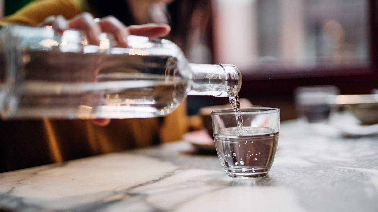 Close up shot of woman pouring water into glass at restaurant