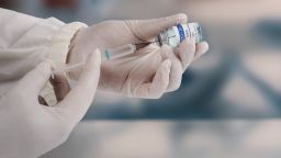 Using a syringe to attack the new covid-19 variant. A young doctor in a white protective glove holds a medical syringe and a vial.