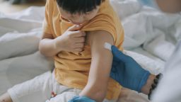 A doctor puts a bandage on a boy's arm after a vaccine injection