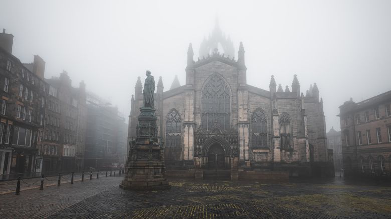 The gothic St Giles' Cathedral in moody atmospheric old town Edinburgh along the cobblestone Royal Mile in misty fog.