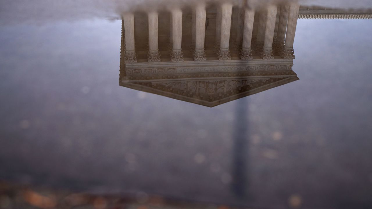 The U.S. Supreme Court building is reflected in a puddle following a rainstorm in Washington, DC.