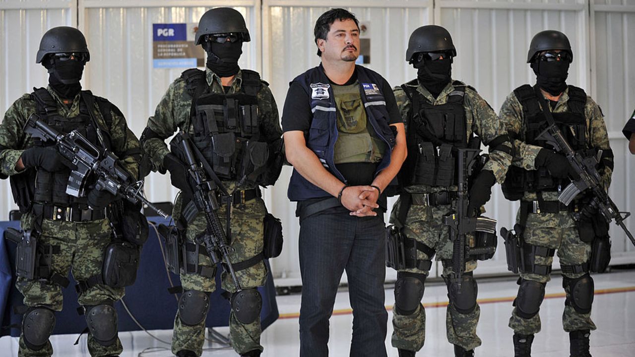 Soldados del ejército mexicano escoltan a Ovidio Limón Sánchez (centro), presunto miembro del cártel de la droga mexicano liderado por Joaquín "El Chapo" Guzmán, durante su presentación en el hangar militar del Aeropuerto Internacional de Culiacán el 10 de noviembre de 2011. Sánchez, considerado por el Departamento de Defensa como "uno de los principales operadores de la organización Guzmán Loera", fue arrestado en Culiacán, Sinaloa (noroeste).