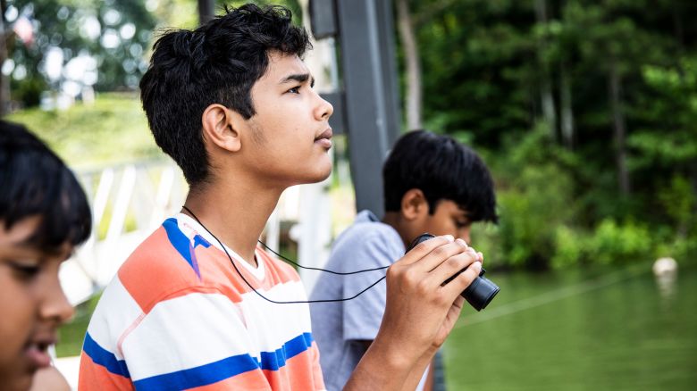 Young boy using binoculars at lake