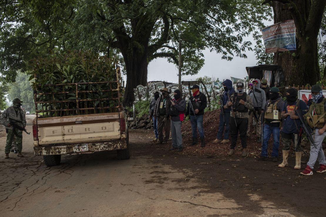 A group of armed men provide security as a truck with avocado trees passes by in Ario de Rosales, Mexico, on July 1, 2021.