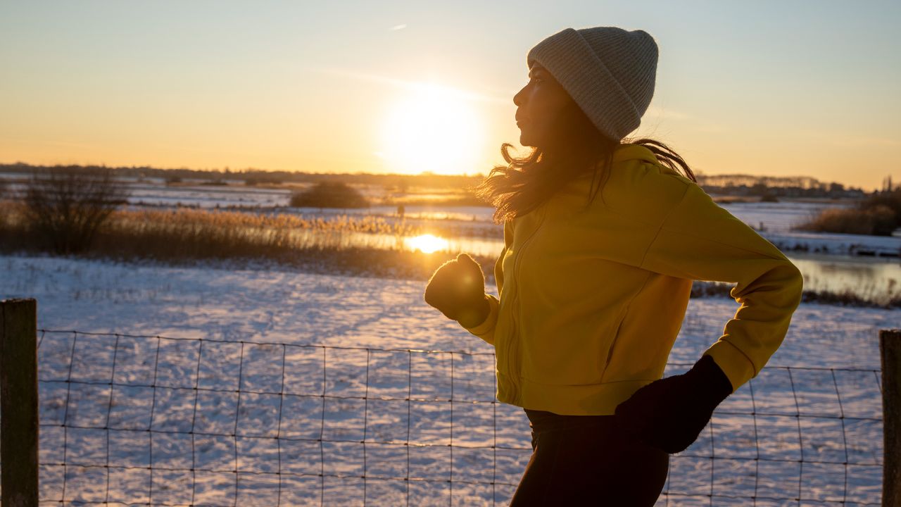 Mature woman wearing knit hat running during winter -