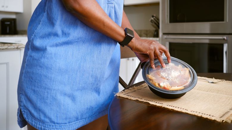 Close-up of unrecognizable black woman removing lid from takeout food container