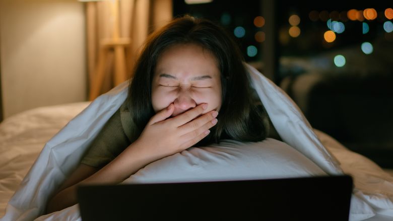 Asian movie addict using laptop watching series on movie stream service online at night.