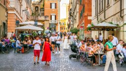 Rome, Italy, July 22 -- Dozens of customer and young adults enjoy life sitting in some outdoor pubs and restaurants in Piazza della Madonna Dei Monti, a picturesque small square in the Rione Monti (Monti district), in the heart of the historic center of Rome. The Monti district is a popular and multi-ethnic quarter much loved by the younger generations and tourists for the presence of trendy pubs, fashion shops and restaurants, where you can find the true soul of the Eternal City. This district, located between the Esquiline Hill and the Roman Forum, is also rich in numerous Baroque-style churches and archaeological remains from the Roman era. In 1980 the historic center of Rome was declared a World Heritage Site by Unesco. Image in high definition format.