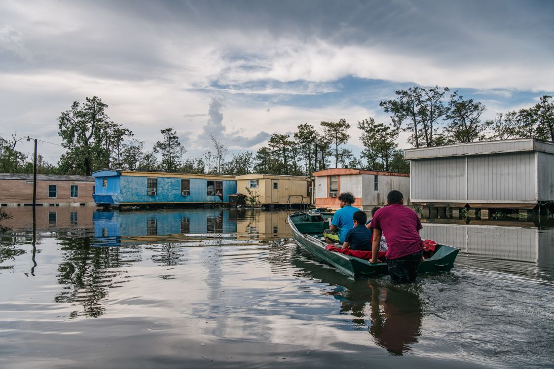 A family travel by boat to their home after it flooded during Hurricane Ida on August 31, 2021 in Barataria, Louisiana.