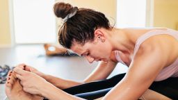 A woman sitting on her towel and touching her toes during a hot yoga class.