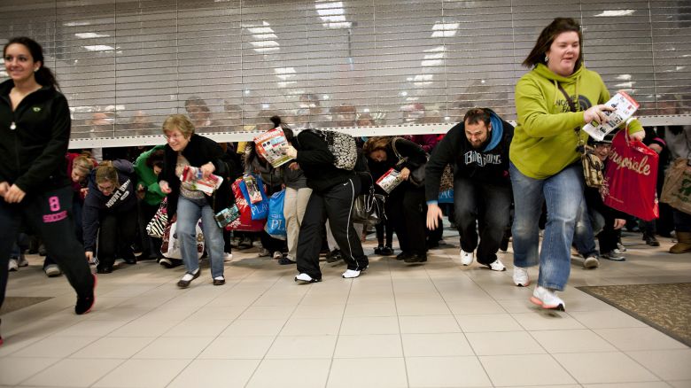 Black Friday shoppers duck under the opening door of a Sears store at Simon Property Group Inc.'s Great Lakes Mall in Mentor, Ohio, U.S., on Friday, Nov. 25, 2011. Black Friday, traditionally the biggest U.S. shopping day of the year, got off to its earliest start ever as retailers tried to woo shoppers with discounts and early store openings.