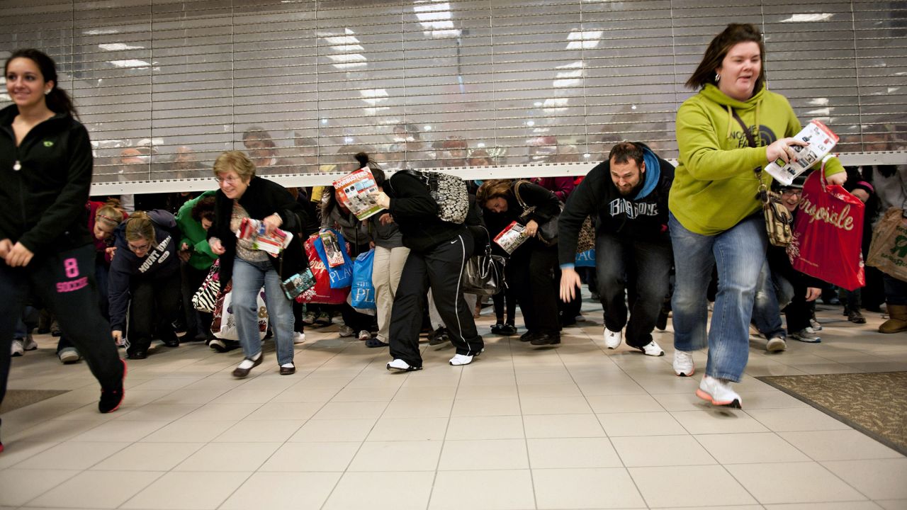 Black Friday shoppers duck under the opening door of a Sears in a 2011 photo.