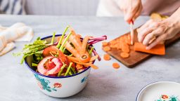 Woman making a fresh vegetable meal while separating leftovers for compost. Zero food waste concept.