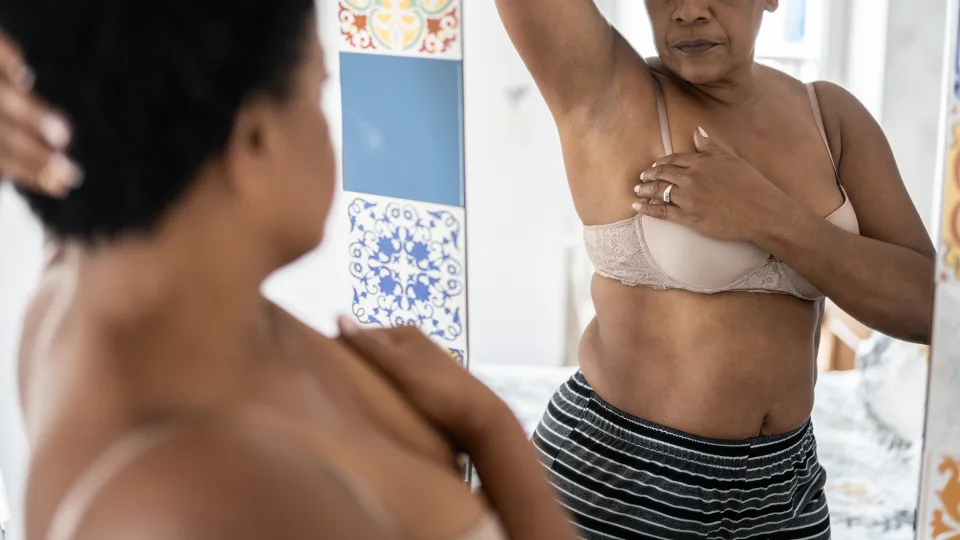 Woman checking herself for breast cancer symptoms. FG Trade/E+/Getty Images