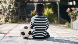 Shot of an adorable little boy sitting outside with his ball