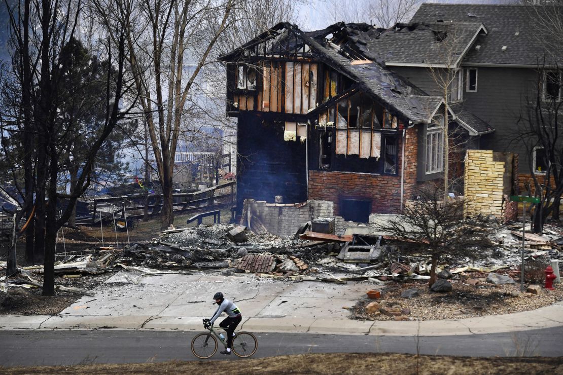 A man on a bike rides by burned homes in the Coal Creek Ranch subdivision in the aftermath of the Marshall Fire on December 31, 2021, in Louisville, Colorado.