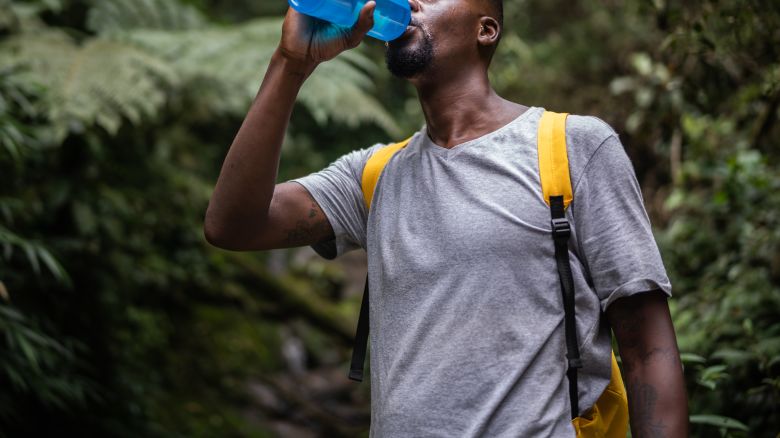 Mid adult man drinking water in the forest