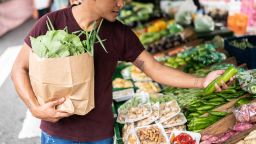 Young man choosing cucumber at a street market